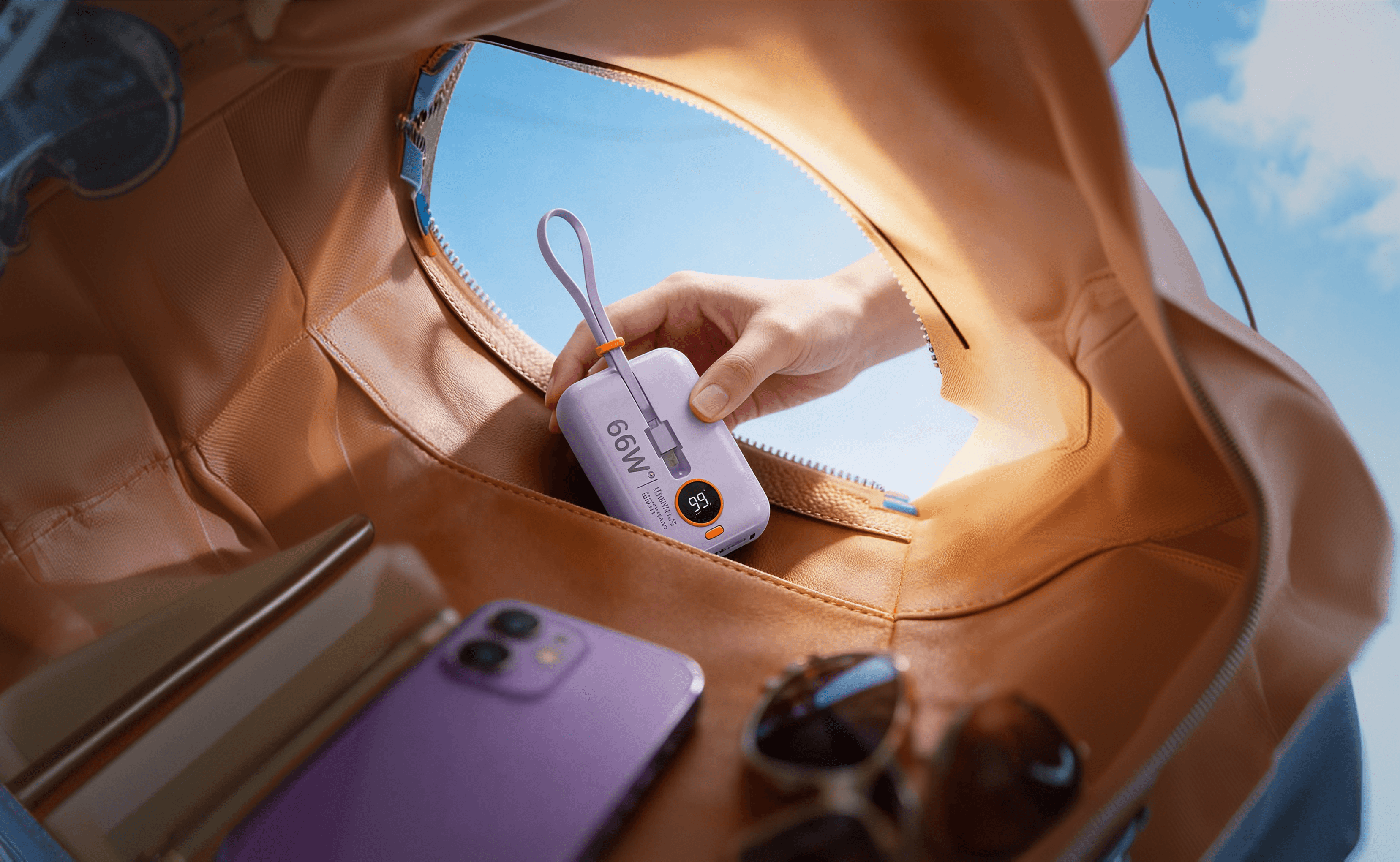 Una bottiglia brandizzata in una borsa color sabbia, accanto a uno smartphone.